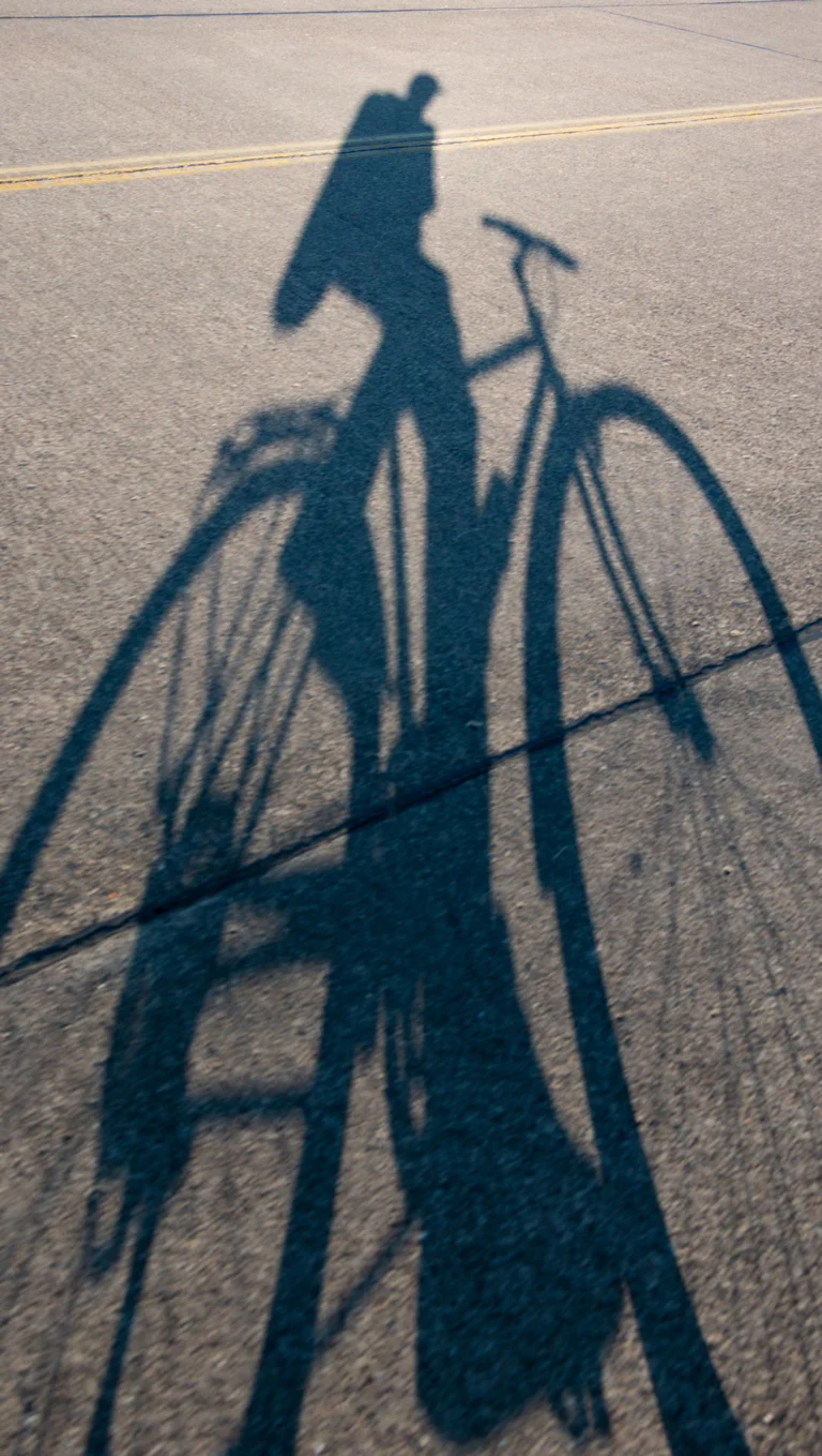 Schatten eines Fahrrads auf dem Asphalt bei Sonnenuntergang