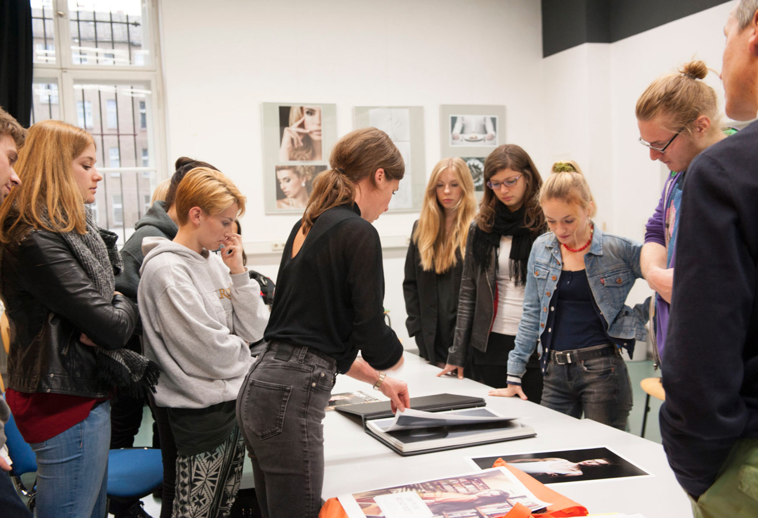 Studierende der Designschule Berlin im Unterricht bei der gemeinsamen Sichtung von Portfolio-Arbeiten mit einer Dozentin.